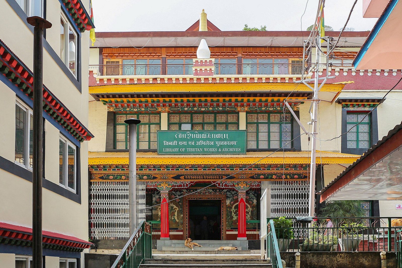 The painted Tibetan-style entrance of the Library of Tibetan Works and Archives, with a sign in Tibetan, Hindi and English