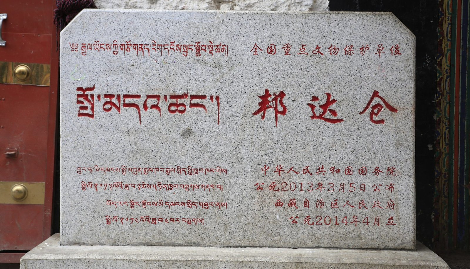 A granite plaque with red inscriptions, Tibetan script on the left and Chinese characters on the right
