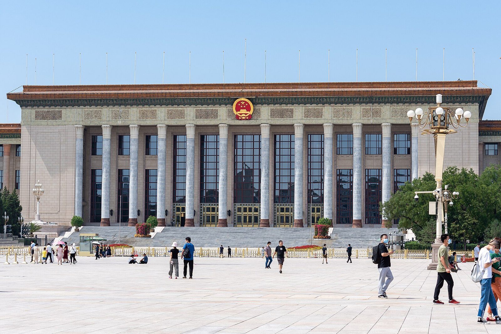 The columned front of the Great Hall of the People in Beijing with the state emblem, a wide paved square in front