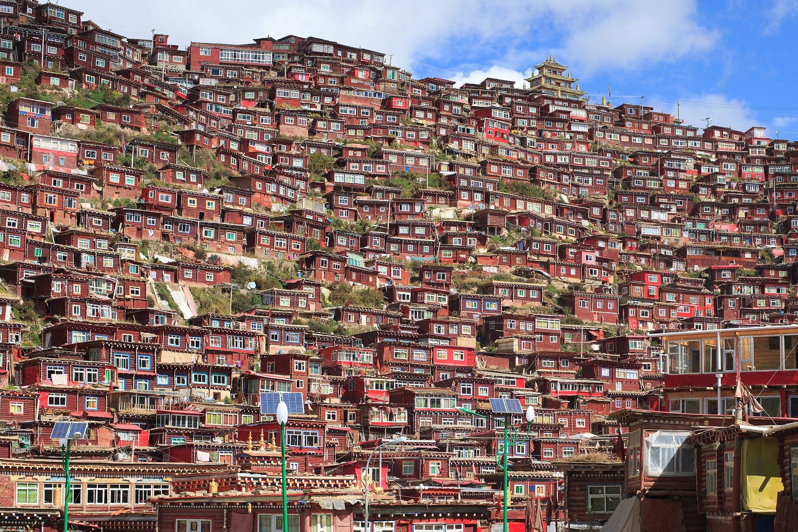 Hundreds of small red wooden houses stacked up a steep hillside under a blue sky