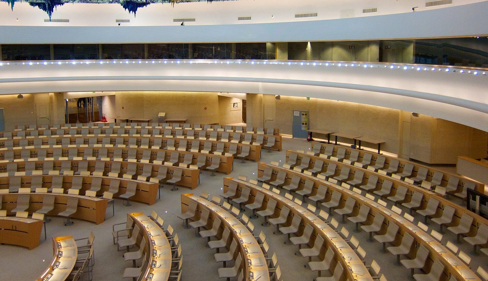 A large circular United Nations assembly hall with curved rows of empty delegates’ desks