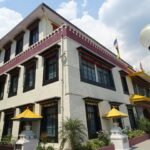 A three-storey Tibetan-style library building with painted window frames and yellow parasols